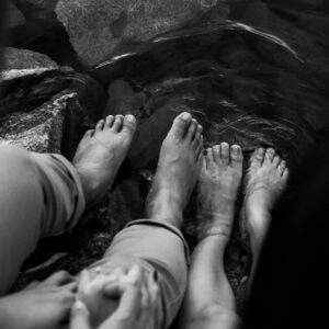 grayscale photo of persons feet on water