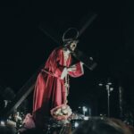 a statue of jesus carrying the cross in the dark