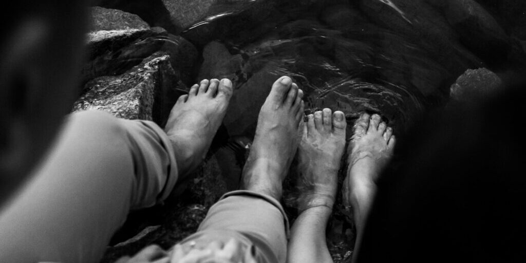 grayscale photo of persons feet on water